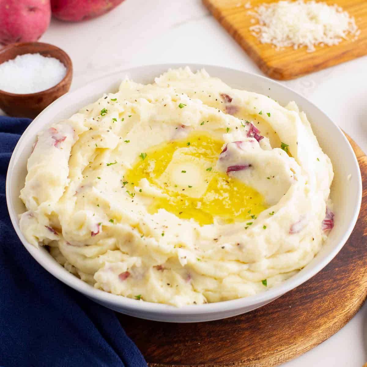 Fluffy mashed potatoes with a pat of butter melting on top in a white bowl